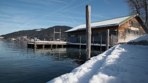 Buildings by lake against sky during winter