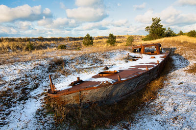 Abandoned boats on field against sky