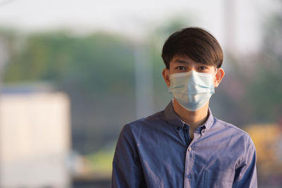 Portrait of teenage boy wearing mask standing outdoors