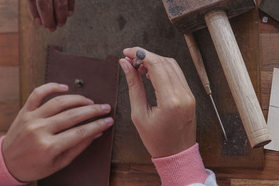 Close-up of hand making leather wallet in workshop