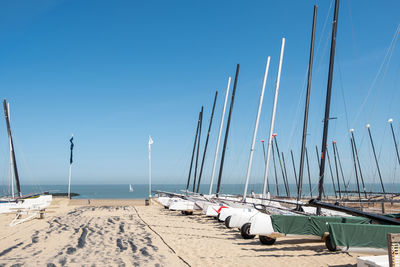 Sailboats moored on beach against clear blue sky