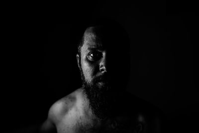 Portrait of bearded man against black background