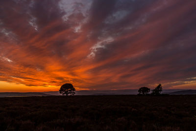 Scenic view of field against dramatic sky during sunset