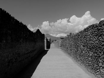 Empty road leading to mountains against sky