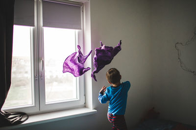 Boy throwing fabrics in room