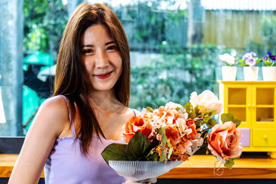 Portrait of smiling young woman holding flower bouquet