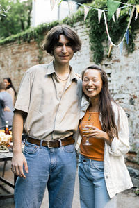 Portrait of smiling man standing with female friend during garden party in back yard