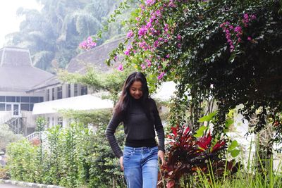 Portrait of smiling young woman standing against plants