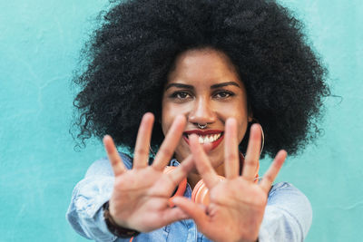 Portrait of smiling young man gesturing against wall