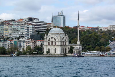 Buildings at waterfront against cloudy sky