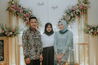 Portrait of smiling young woman standing against wall