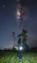 Trees on field against sky at night