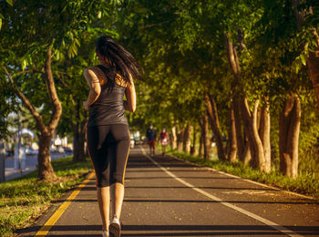 Full length of young woman walking on footpath in park