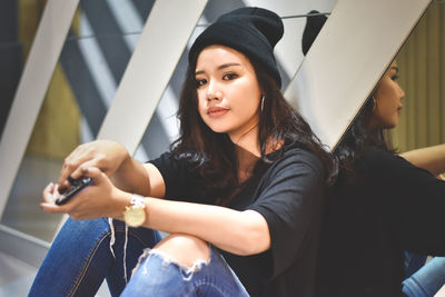 Young woman using mobile phone while sitting on camera
