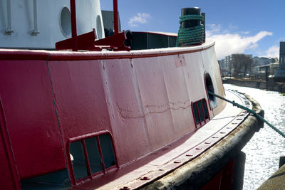 Old boat moored on shore against sky