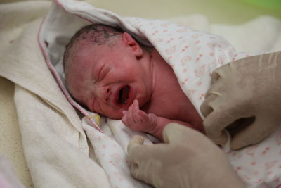 Cropped hands of doctor wrapping newborn girl in baby blanket