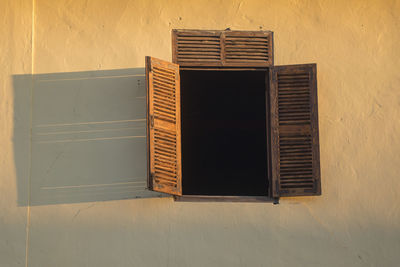 Low angle view of open brown wooden window of house