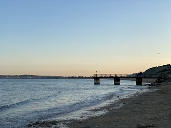 Bridge over calm sea against clear sky