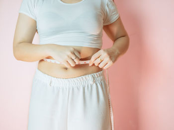 Midsection of woman standing against white wall