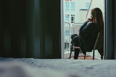 Young woman sitting on bed at home