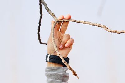 Close-up of hand holding rope against white background