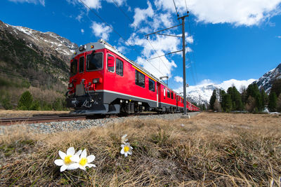 Red train on railroad track against sky