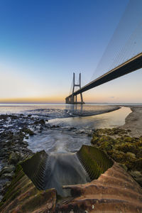 Cable-stayed bridge over river during sunset