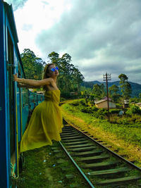 Woman standing by railroad tracks against sky