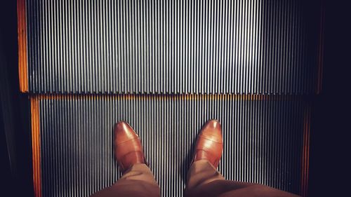 Low section of businessman standing on escalator