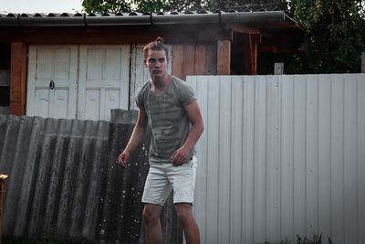 Portrait of young man standing against built structure