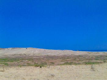 Scenic view of sand dunes against clear blue sky