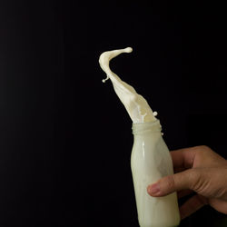 Close-up of hand holding ice cream against black background