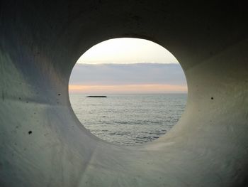Scenic view of sea during sunset seen through hole