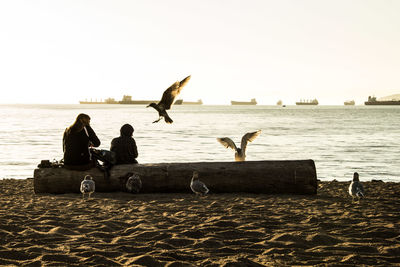 People on boat in sea against clear sky