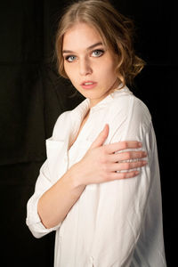 Portrait of beautiful woman standing against black background