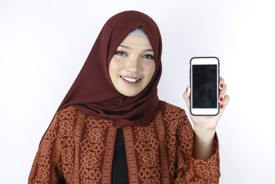 Portrait of smiling young woman holding smart phone
