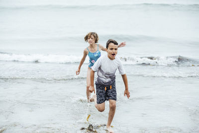 Playful siblings running in sea