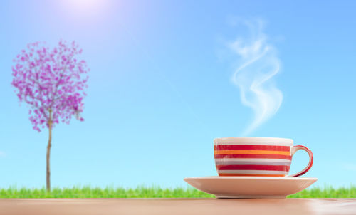 Close-up of coffee cup on table against blue sky