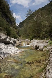 Scenic view of river stream amidst mountains against sky