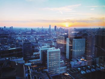 Aerial view of buildings in city against sky during sunset