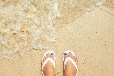 Low section of woman standing at sandy beach