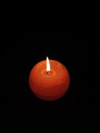 Close-up of lit candle against black background