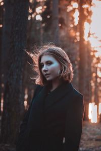 Portrait of woman standing against tree