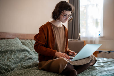 Concentrated pensive teen girl working as freelancer, studying online at home using laptop computer