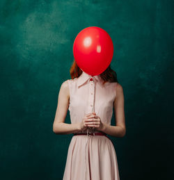 Midsection of woman with balloons against wall
