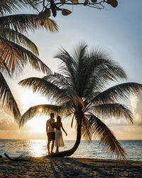 Romantic young couple together on beautiful exotic tropical beach under palms at sunset