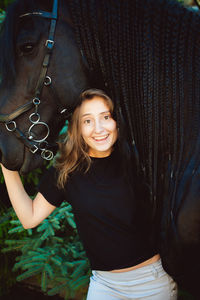 Portrait of young woman standing with horse