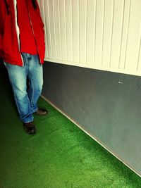 Low section of man standing on floor against wall