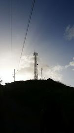 Low angle view of silhouette electricity pylon against sky