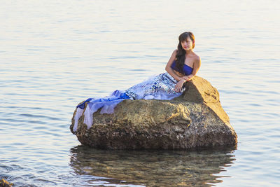 Portrait of young woman sitting on rock